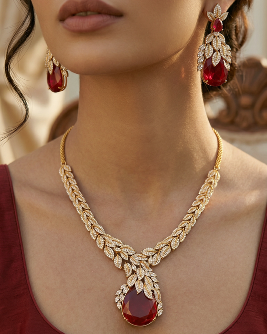 Woman wearing a gold necklace with ruby red doublet stones and matching earrings.