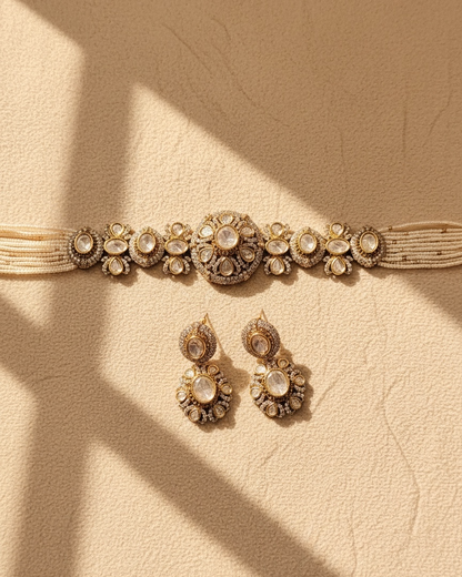 Gold jewelry set with necklace and earrings on a beige background