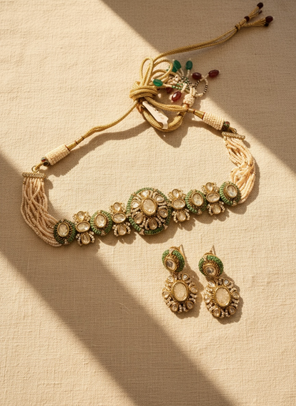 Decorative necklace and earrings with green and gold details on a beige background